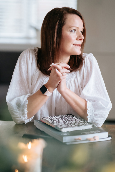 Marie-claire looking off into the distance with a workbook at a table